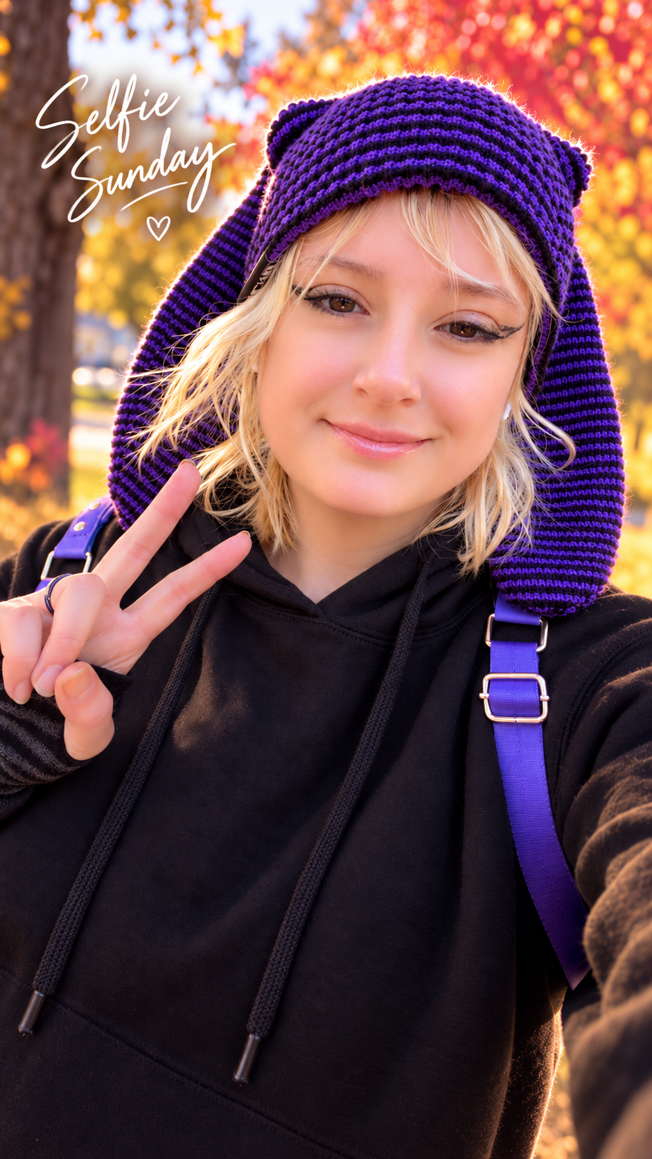 Miki smiling outdoors in a purple knit hat on a warm autumn day